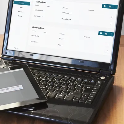 Render of WingMDM page on a laptop, with an iPad being prepared for onboarding.